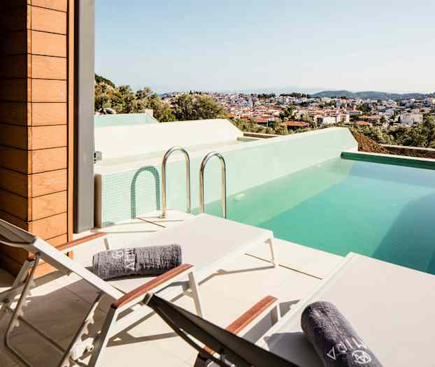 Terrasse med solsenger og et basseng, med utsikt over en by. (AI-generert tekst)