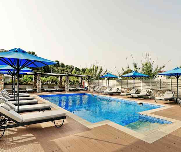 Et utendørsbasseng omgitt av solsenger og parasoller. (AI-generert tekst)