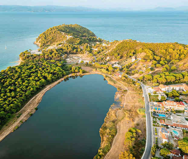 Luftfoto av en kyst med skog, en stor innsjø og bygninger. (AI-generert tekst)