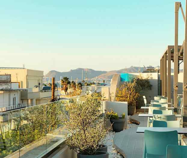 Bilde av en takterrasse med sitteplasser og beplantning, med utsikt over byen og fjell i bakgrunnen. (AI-generert tekst)