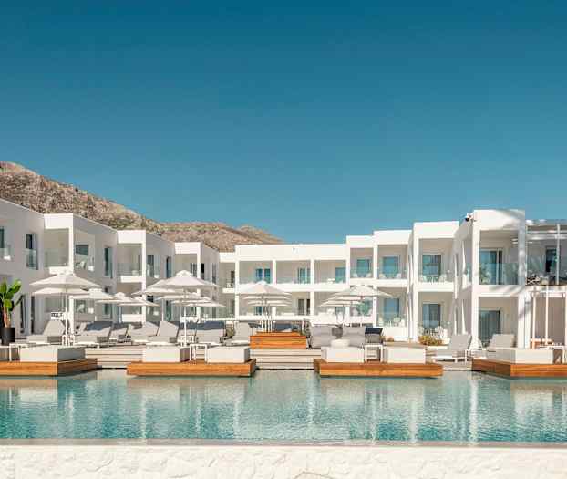 Hvit hotellbygning med utendørsbasseng og solsenger. (AI-generert tekst)