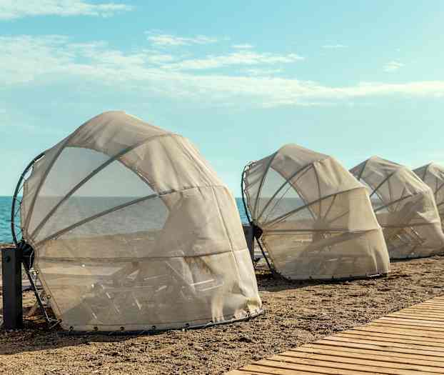 Beskyttede solsenger på stranden nær sjøen. (AI-generert tekst)