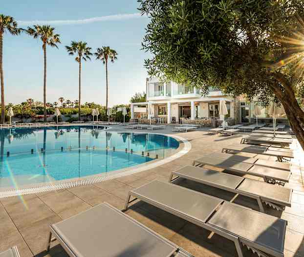 Utendørsbasseng med solsenger og palmer i bakgrunnen. (AI-generert tekst)