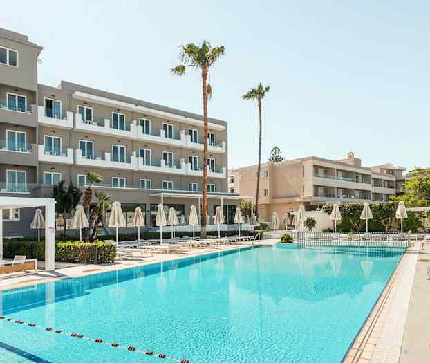 Bilde av et hotell med balkonger, et basseng samt solsenger og parasoller. (AI-generert tekst)