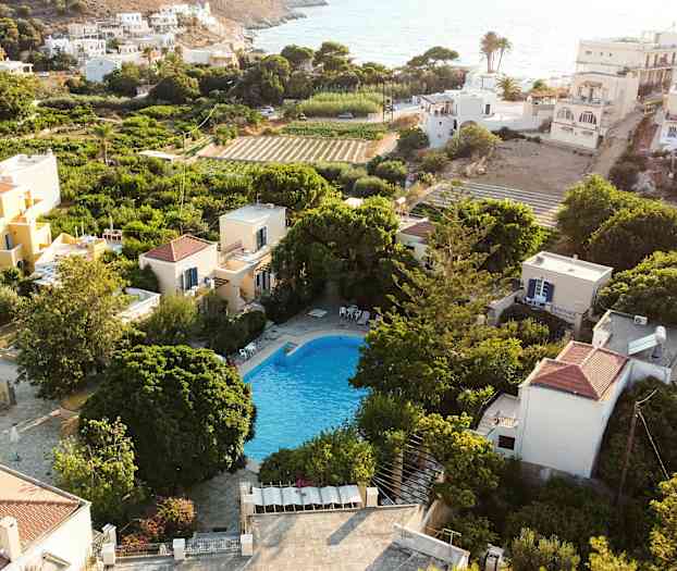 Utsikt over et basseng omgitt av grøntområder og hus i et solrikt område. (AI-generert tekst)