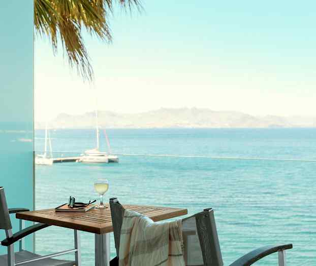 Utsikt over havet fra en terrasse med bord og stoler. (AI-generert tekst)