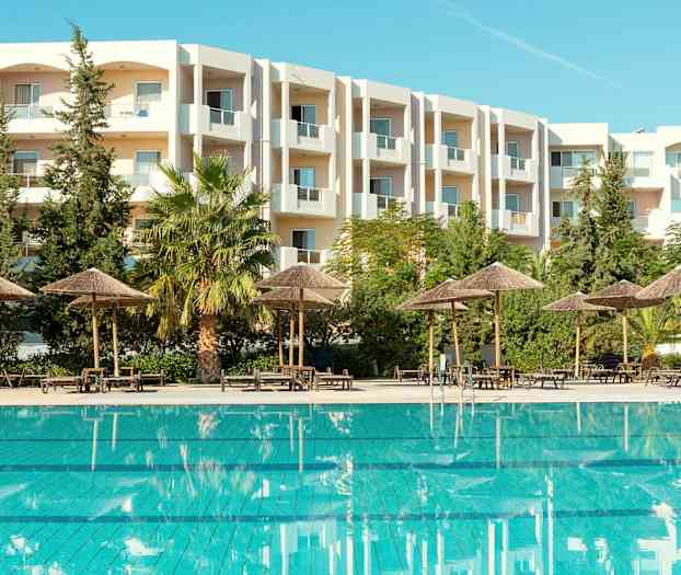 Utendørsbasseng med parasoller og en hvit bygning i bakgrunnen. (AI-generert tekst)