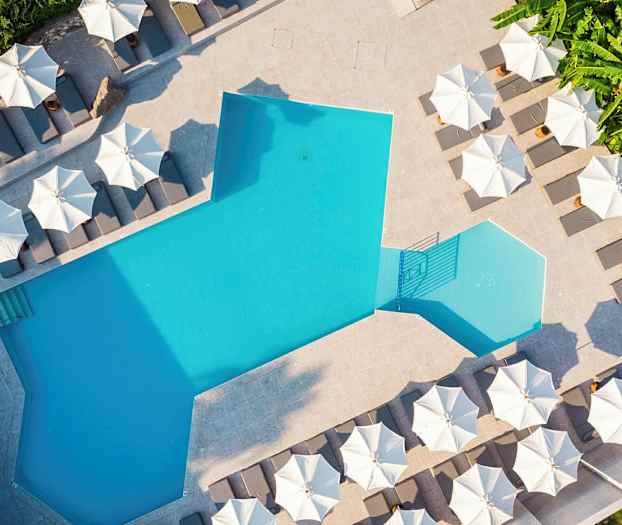 Et svømmebasseng med solsenger og parasoller rundt. (AI-generert tekst)