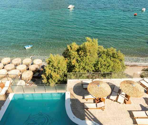 Bassengområde med solsenger og parasoller nær stranden og havet. (AI-generert tekst)