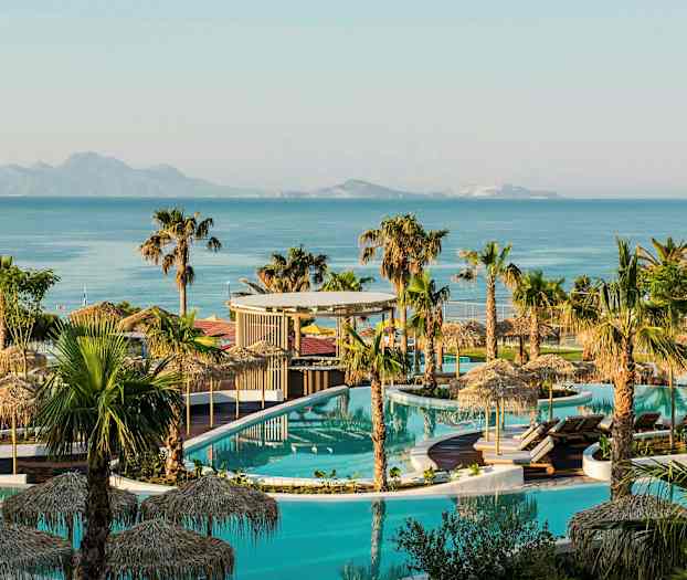 Bilde av et bassengområde med palmer, parasoller og hav i bakgrunnen. (AI-generert tekst)