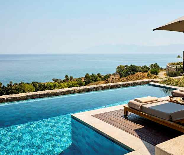 Et infinity-basseng med utsikt over havet og et frodig landskap. (AI-generert tekst)