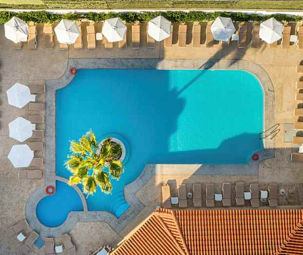 En fugleperspektivvisning av et rektangulært basseng med solsenger og parasoller rundt. (AI-generert tekst)