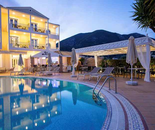 Hotellfasade med basseng og solsenger i forgrunnen. (AI-generert tekst)