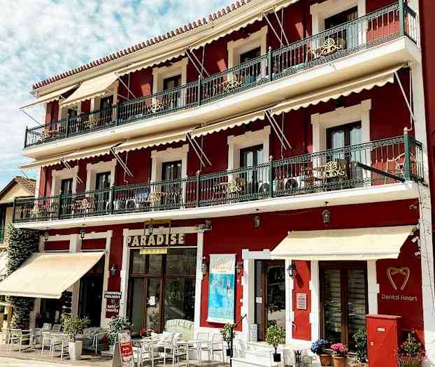 Rød bygning med tre etasjer, balkonger og skilt, inkludert 'Paradise'. (AI-generert tekst)