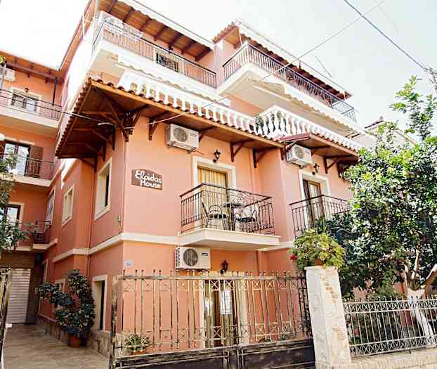 En bygning malt i rødt med flere balkonger og gjerder foran. (AI-generert tekst)