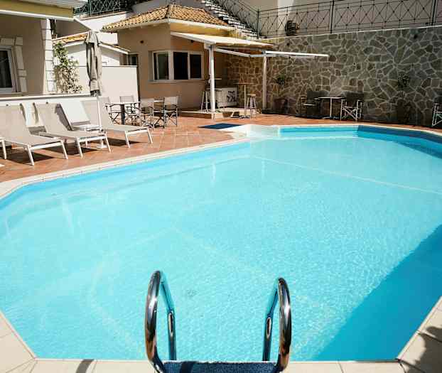 Utendørsbasseng med solsenger og parasoller ved siden av. (AI-generert tekst)