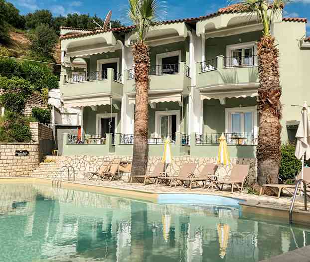 Leilighetskompleks med basseng og solsenger foran. (AI-generert tekst)