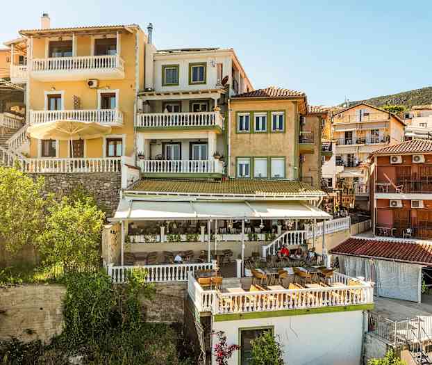 Flere bygninger med fargerike fasader og terrasser er synlige, plassert på en skråning. (AI-generert tekst)