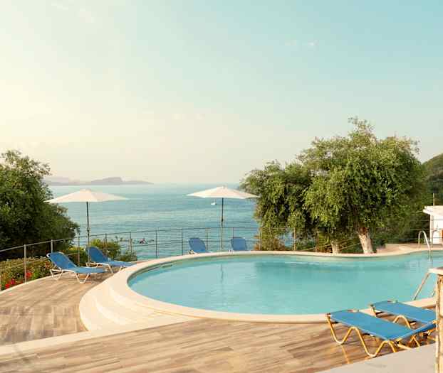 Utendørsområde med et basseng, solsenger og utsikt over havet. (AI-generert tekst)