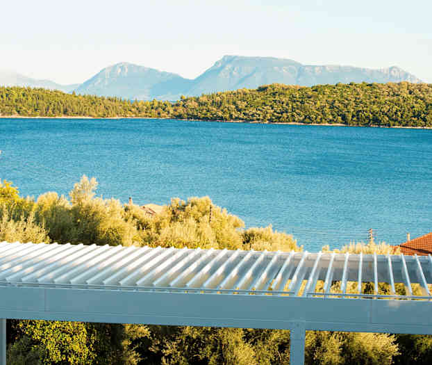 Utsikt over havet med trær og en terrasse i forgrunnen. (AI-generert tekst)