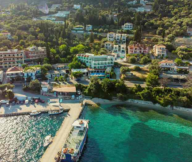 Luftfoto av en kystby med hus og grøntområder ved vannet. (AI-generert tekst)
