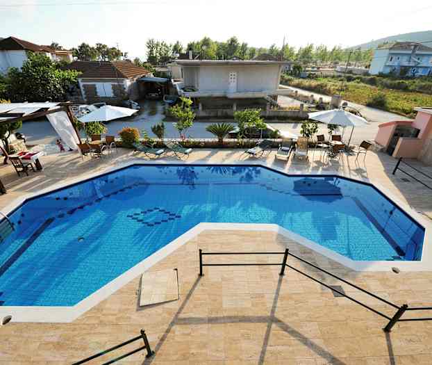 Utendørsbasseng med solsenger og parasoller rundt, samt bygninger i bakgrunnen. (AI-generert tekst)