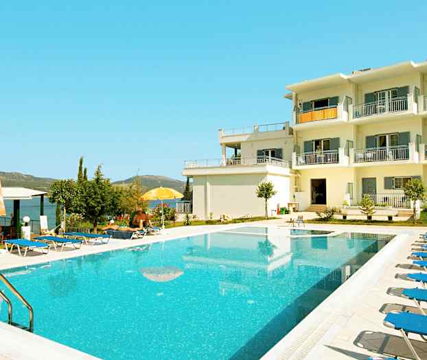 Et utendørsbasseng ved en hvit bygning med balkonger. (AI-generert tekst)