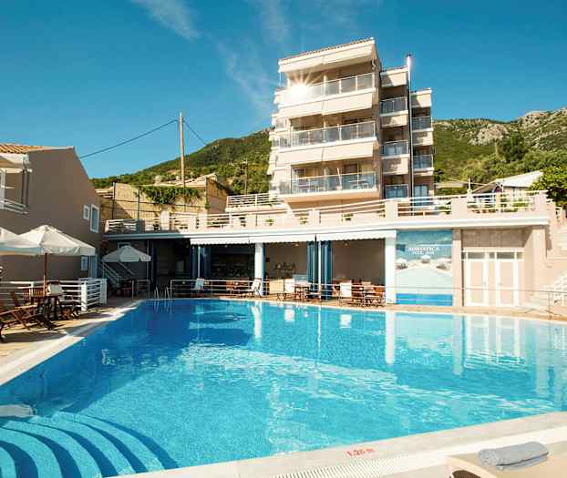 Bilde av en bygning med glassbalkonger, et basseng foran og solsenger rundt. (AI-generert tekst)