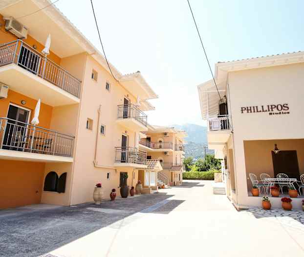 Bygninger med balkonger og gjennomgående beige fasader samt dekorasjoner med blomster i potter. (AI-generert tekst)