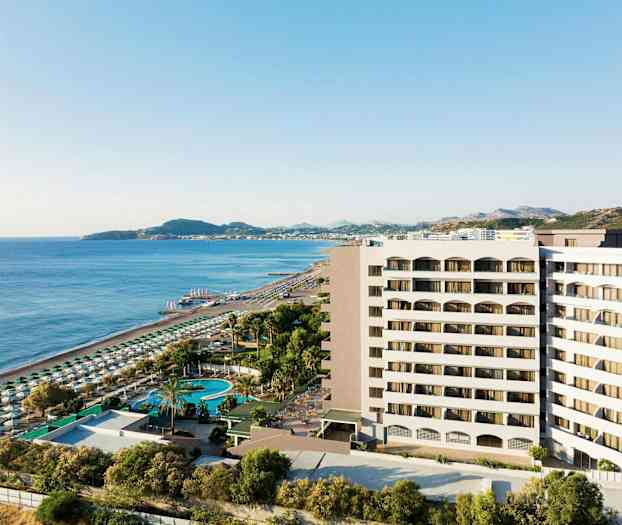 Utsikt over hotellbygning nær sandstrand og hav med solsenger og parasoller. (AI-generert tekst)