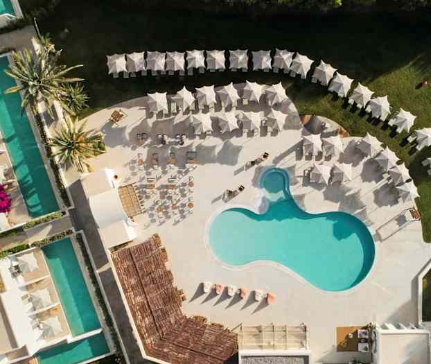 Flyfoto av et bassengområde med solsenger og parasoller. (AI-generert tekst)