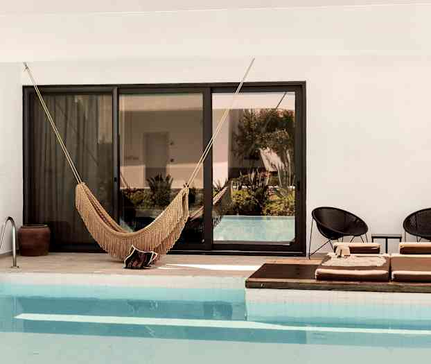 Bilde av et basseng med en hengekøye og solsenger ved kanten. (AI-generert tekst)