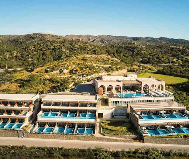 Hotellkompleks med flere bygninger og private bassenger, plassert i naturlandskap med fjell og vegetasjon. (AI-generert tekst)