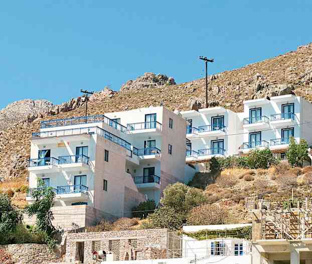 Hvit bygning med blå balkongrekkverk ved en fjellskråning. (AI-generert tekst)