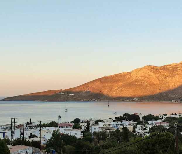 Strandby med seilbåter og fjell i bakgrunnen. (AI-generert tekst)