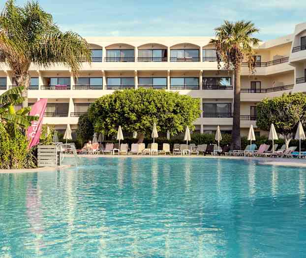 Hotell med basseng og solsenger i forgrunnen. (AI-generert tekst)