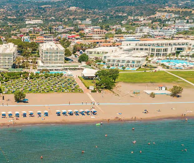 Hotellkompleks ved en sandstrand med solsenger og parasoller. (AI-generert tekst)