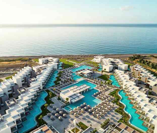 Flyfoto av en hotellresort med bassenger nær sjøen. (AI-generert tekst)