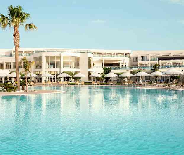 Bassengområde ved en moderne hotellbygning med solsenger og parasoller. (AI-generert tekst)