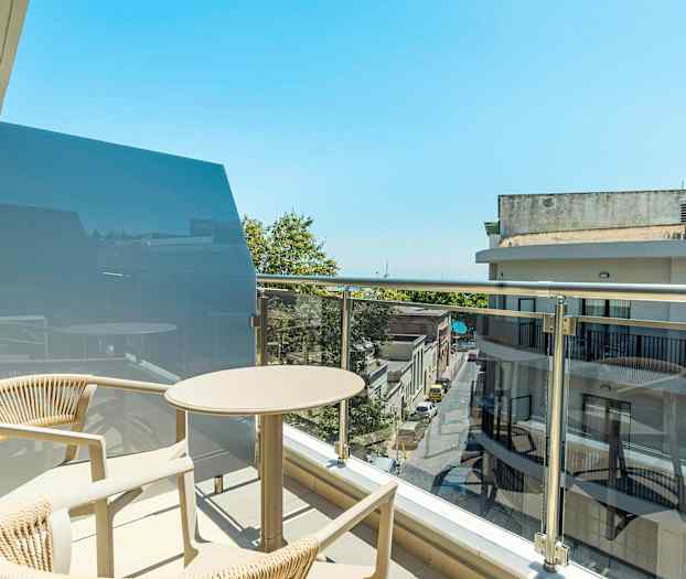 En balkong med bord og stoler i en bymiljø. (AI-generert tekst)