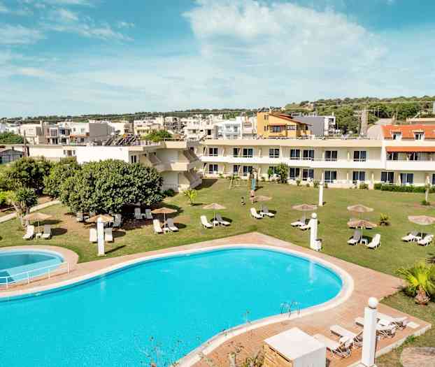 Et bilde av et basseng med solsenger og parasoller på en gressplen, omgitt av bygninger. (AI-generert tekst)