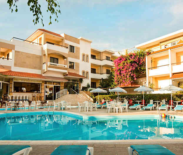 Hotellbygning med et svømmebasseng i forgrunnen, omgitt av solsenger og parasoller. (AI-generert tekst)