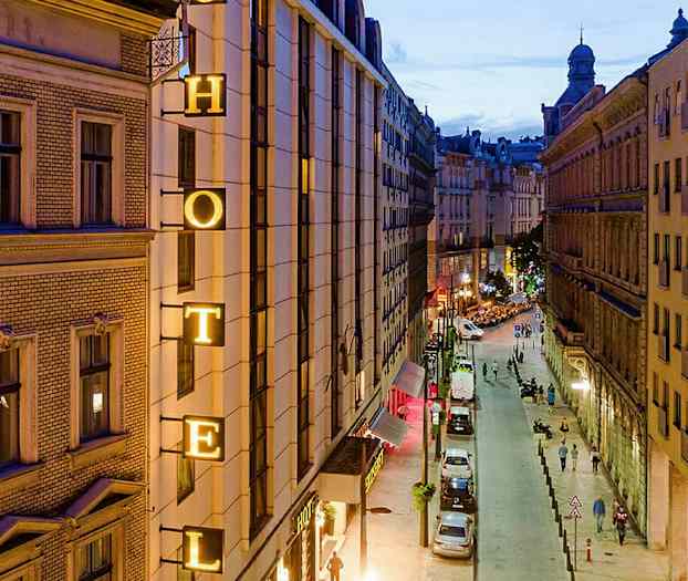 Bilde av en bygate om kvelden med et hotellskilt på en bygning. (AI-generert tekst)