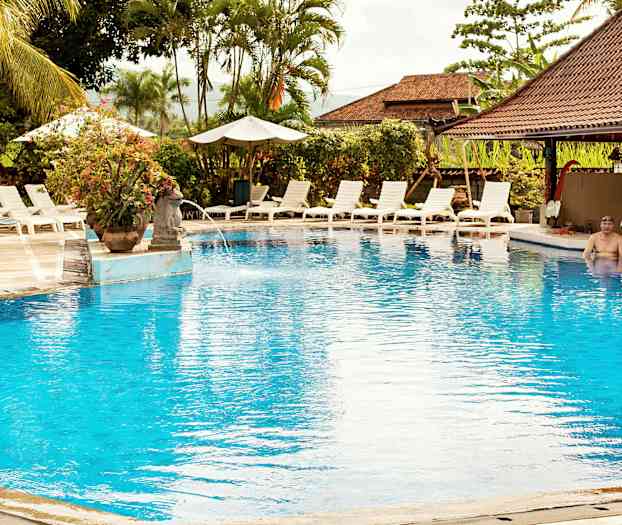 Et utendørsbasseng omgitt av solsenger og parasoller. (AI-generert tekst)