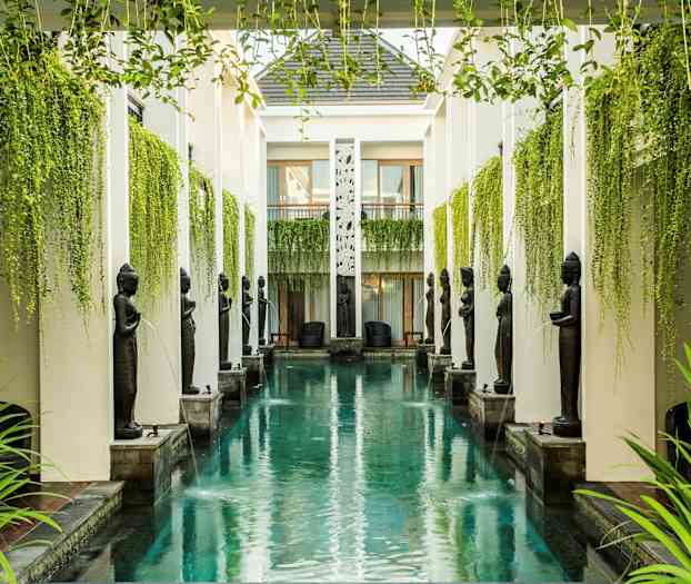 Et langt, smalt basseng omgitt av søyler, statuer og hengende grønt. (AI-generert tekst)