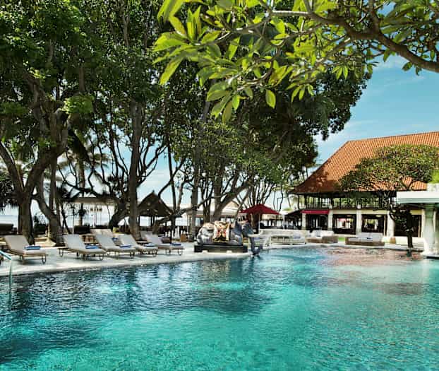 Et basseng i en hage omgitt av solsenger og grønne omgivelser. (AI-generert tekst)