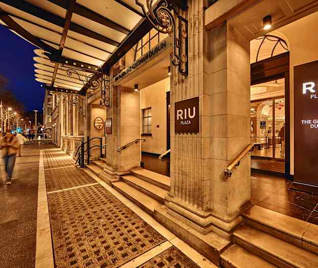 Hotel RIU Plaza Gresham Dublin inngang med opplyste skilt, kveldsmiljø. (AI-generert tekst)
