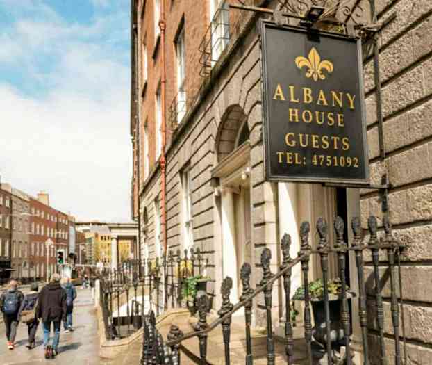 Skilt med teksten Albany House Guests ved en husfasade. (AI-generert tekst)