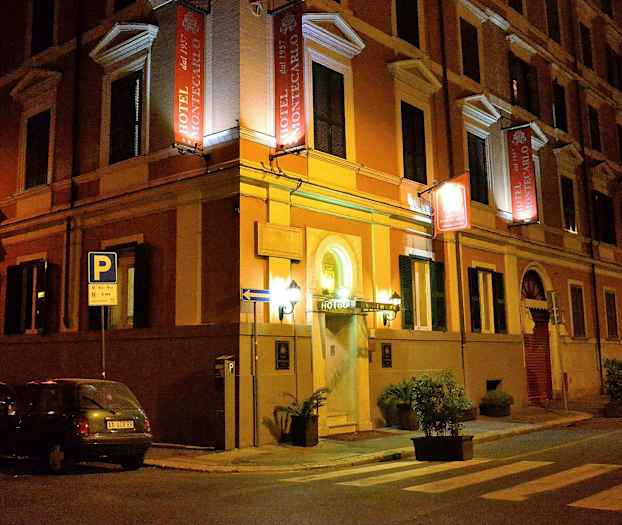 Et hotell med navnet Hotel Montecarlo ligger i et gatehjørne om kvelden. (AI-generert tekst)