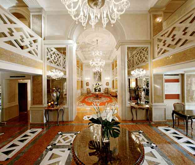 En elegant hotellobby med lysekroner, speil og et sentralt bord med blomster. (AI-generert tekst)